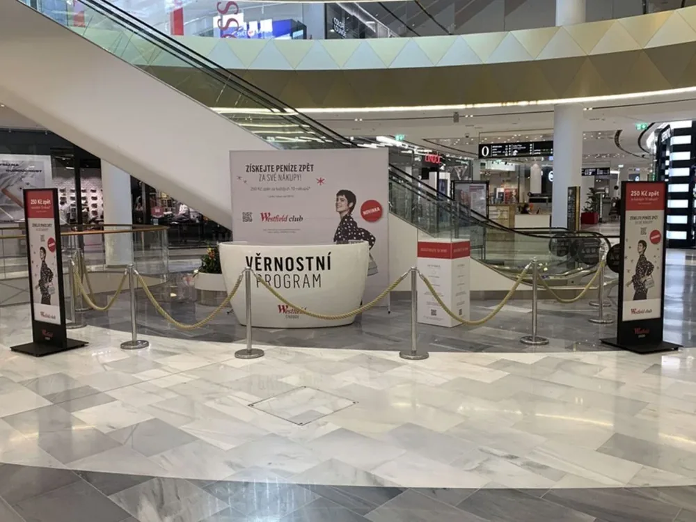 Mobilní poutače věrnostního programu rozmístěné u eskalátorů obchodního centra