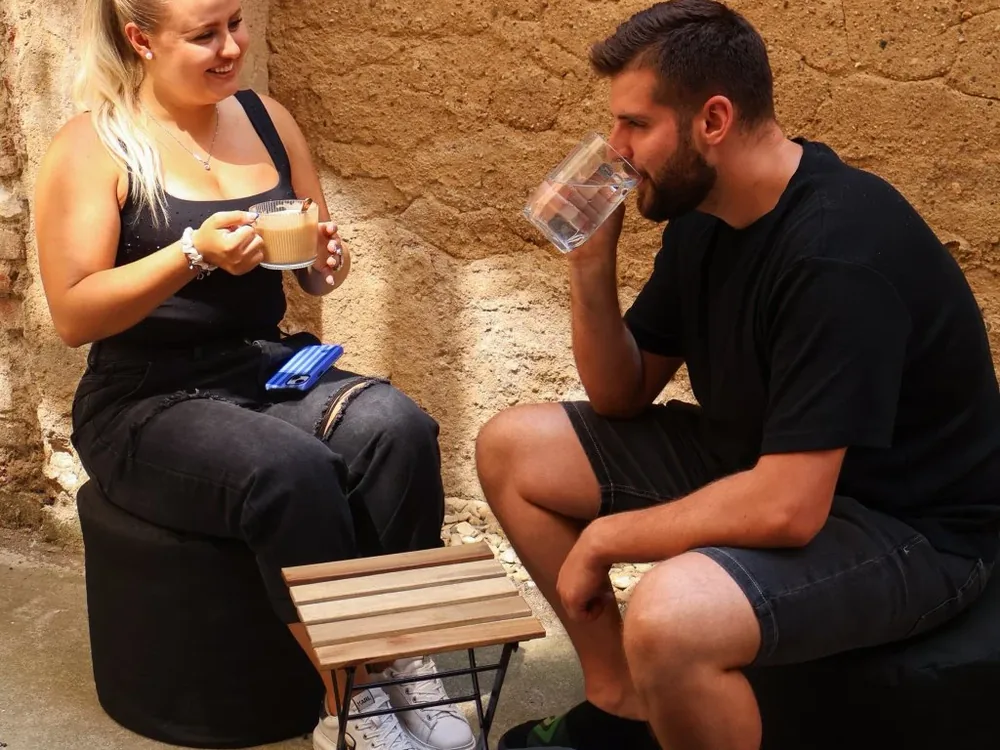 Hosté sedící na kulatých taburetech s firemním potiskem na venkovní akci